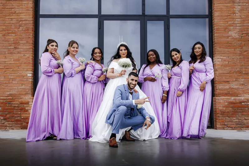 Couple de mariés posant avec les demoiselles d'honneur en robes lilas