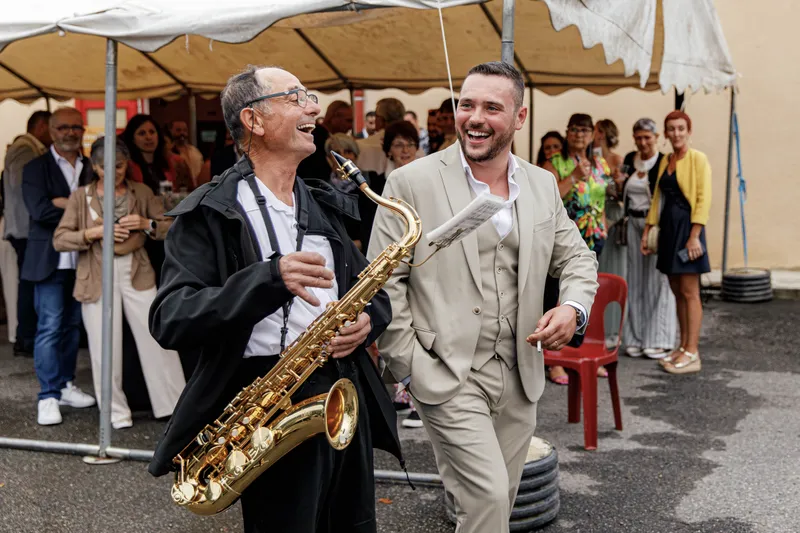 Marié riant avec un saxophoniste lors du vin d'honneur