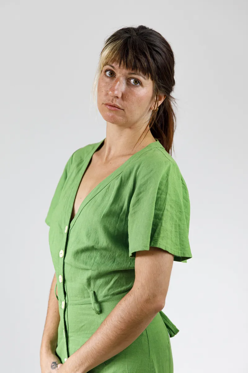 Portrait d'une comédienne de profil en robe verte sur fond clair