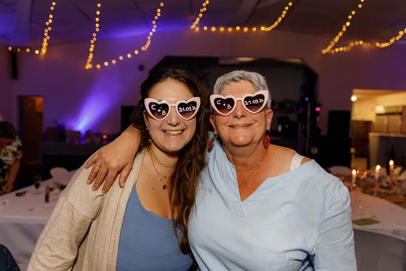 Deux invitées posant avec des lunettes en forme de coeur lors d'une soirée de mariage