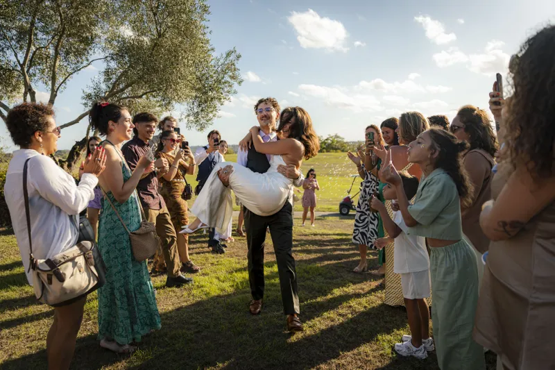 Marié portant la mariée dans ses bras devant les invités applaudissant