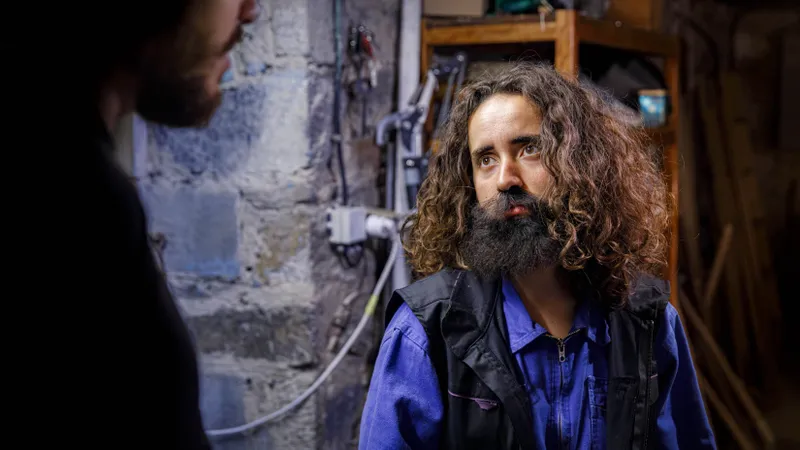 Portrait d'un comédien barbu aux cheveux bouclés en bleu de travail
