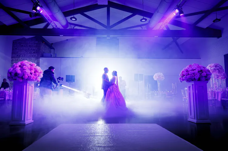 Silhouette d'un couple de mariés dansant dans la brume sous un éclairage violet