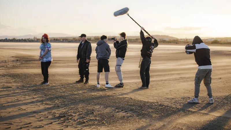 Équipe de tournage filmant un clip sur une plage au coucher du soleil