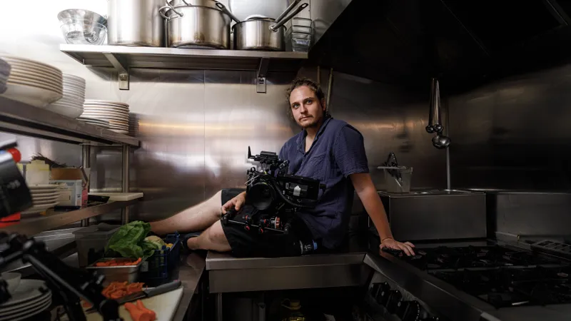 Cadreur assis sur un plan de travail de cuisine avec sa caméra
