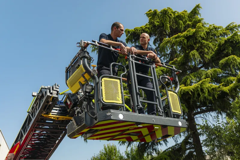 Deux pompiers en haut de la grande échelle avec vue sur les arbres