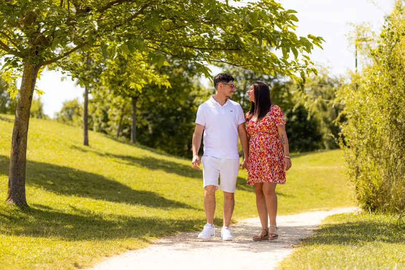 Couple se promenant main dans la main sous les arbres en été
