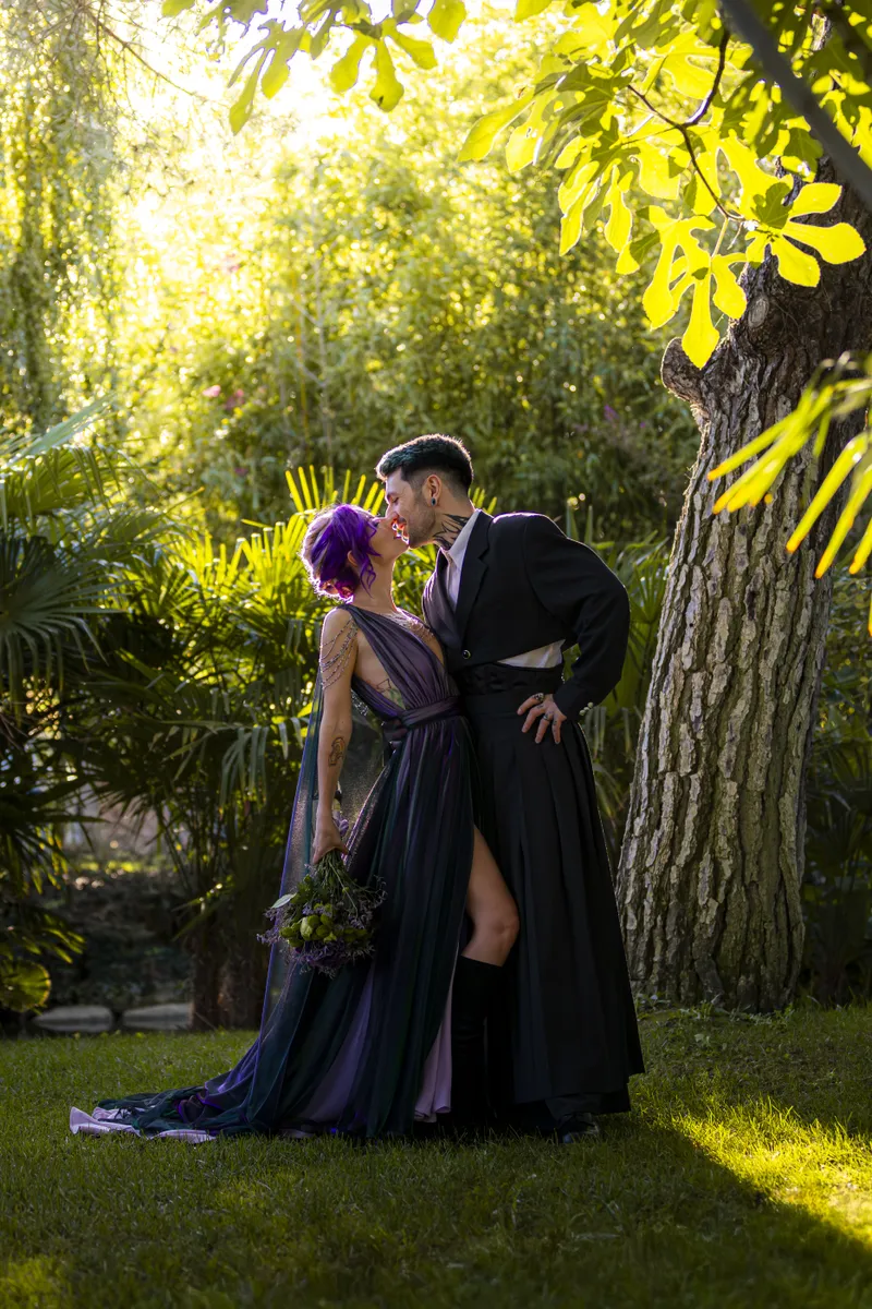 Couple de mariés s'embrassant sous un arbre dans un jardin ensoleillé