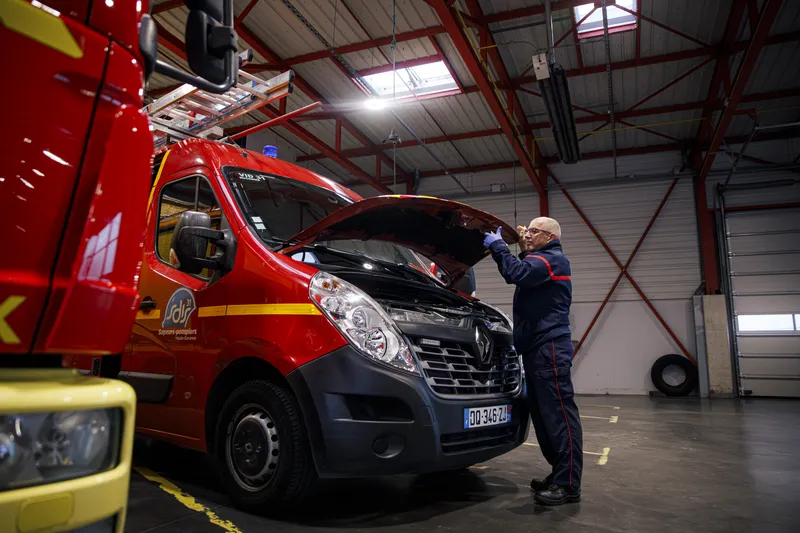 Pompier mécanicien vérifiant le moteur d'un véhicule de secours dans l'atelier