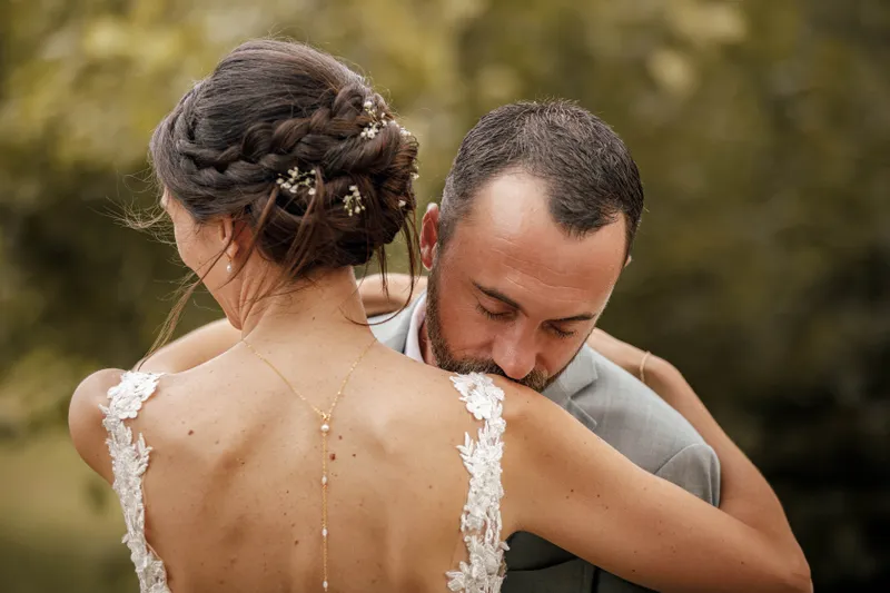 Mariée et marié enlacés, vue sur le dos nu de la robe et la coiffure tressée
