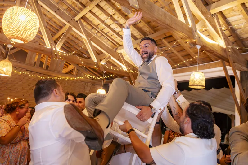 Marié soulevé sur une chaise par ses amis lors de la soirée de mariage