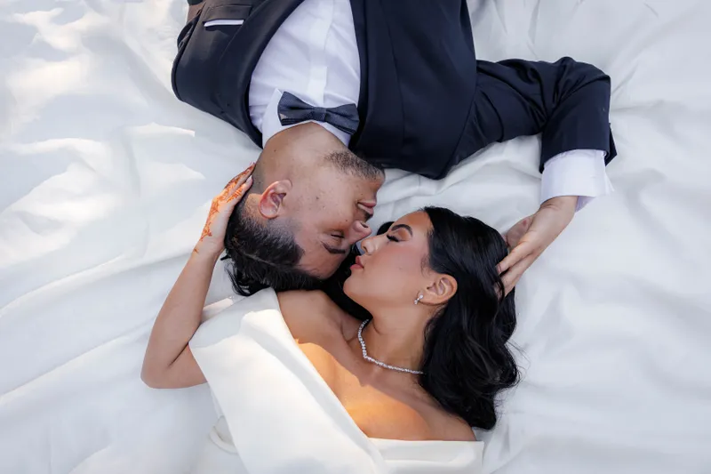 Mariés allongés face à face sur un tissu blanc, vue du dessus