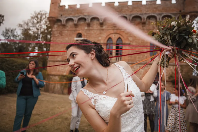 Mariée jouant au jeu du ruban devant un château en briques