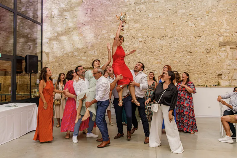 Invitée soulevée en l'air par un groupe joyeux lors d'une réception de mariage
