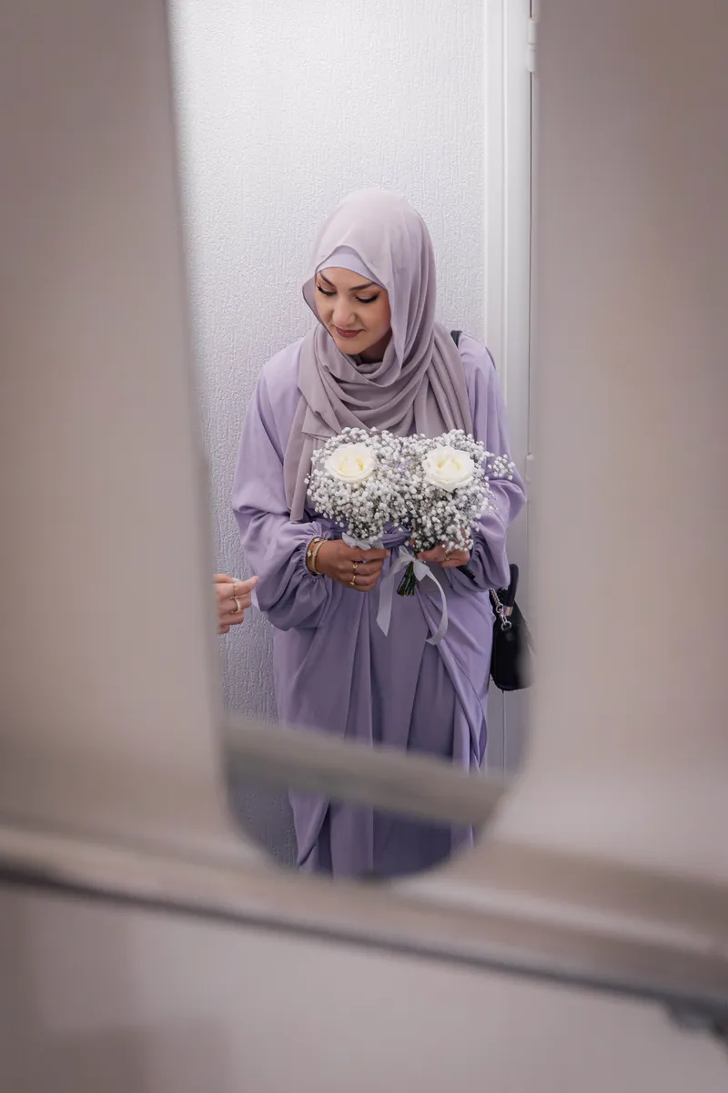 Demoiselle d'honneur en hijab tenant un bouquet dans le reflet d'un miroir