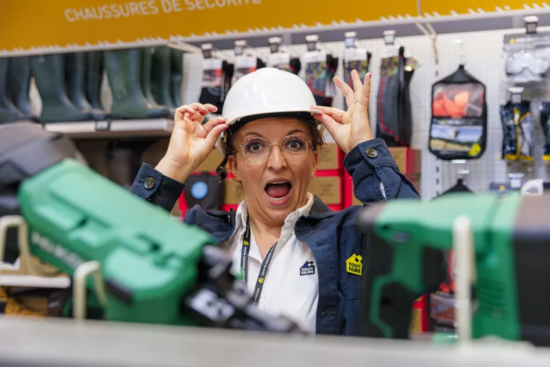Employée surprise portant un casque de chantier dans un magasin de bricolage