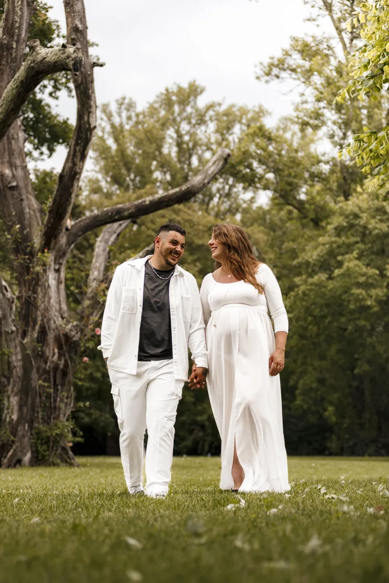 Couple se promenant main dans la main dans un parc en attendant bébé
