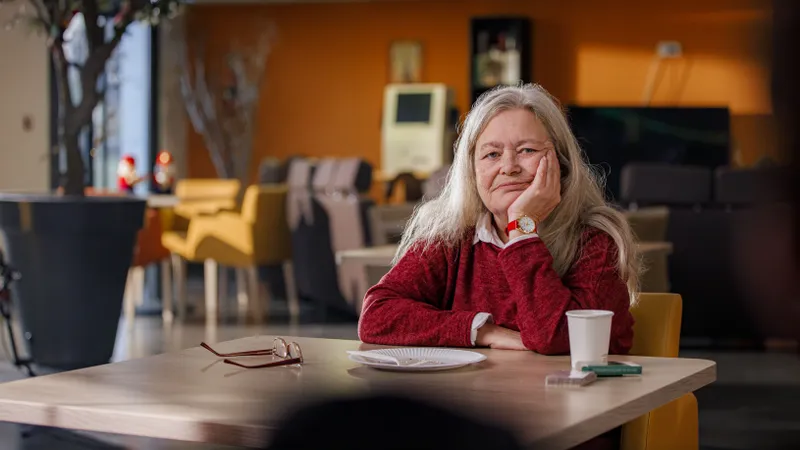 Comédienne aux cheveux longs attablée dans un décor de café chaleureux