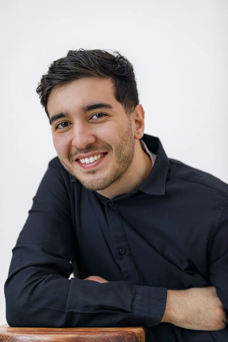 Portrait souriant d'un comédien en chemise noire sur fond clair