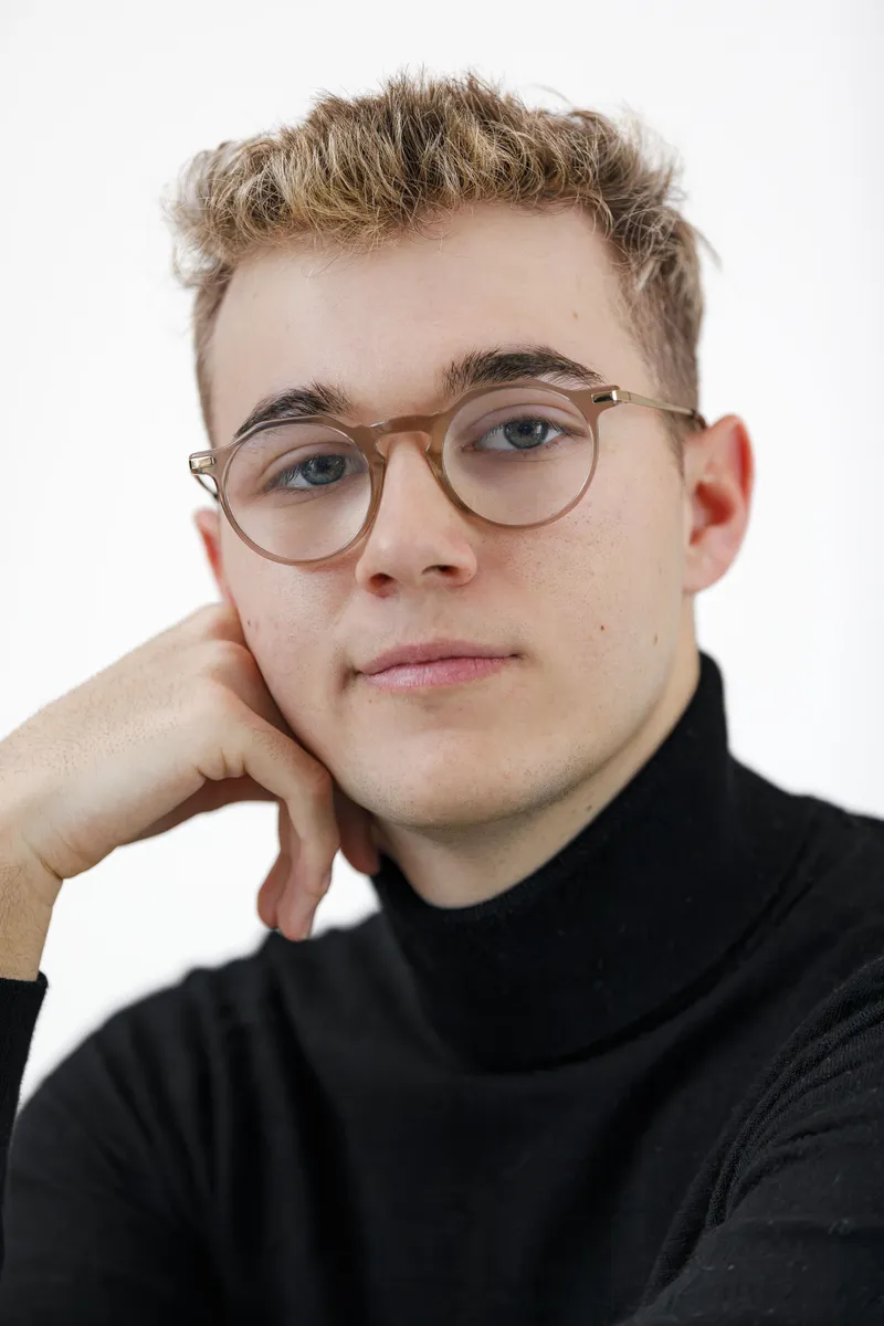 Portrait rapproché d'un jeune comédien en col roulé noir avec lunettes