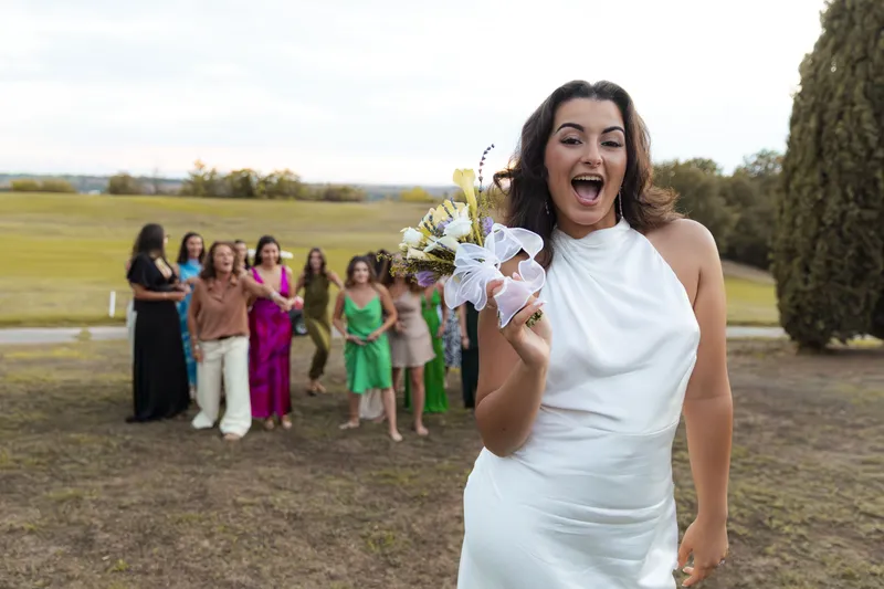 Invitée attrapant le bouquet de la mariée avec joie devant les autres invitées