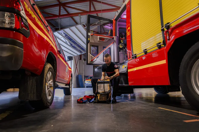 Pompier préparant son équipement entre deux camions dans la caserne