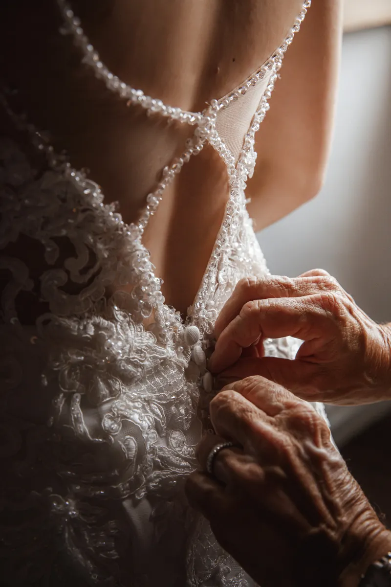 Mains boutonnant le dos de la robe de mariée en dentelle