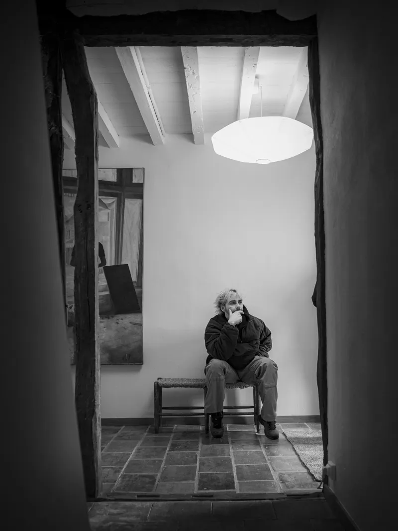 Portrait en noir et blanc d'un homme assis dans l'embrasure d'une porte