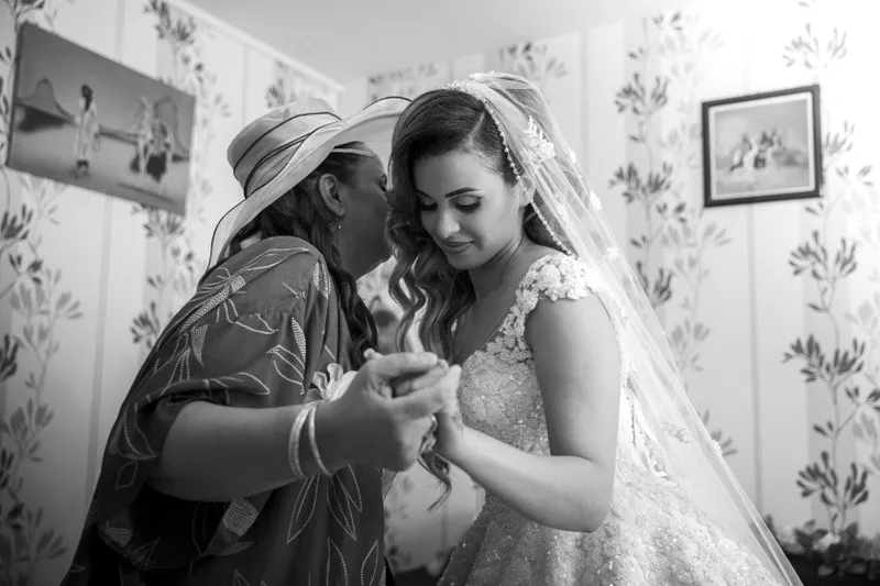 Mère aidant la mariée à mettre ses bijoux en noir et blanc