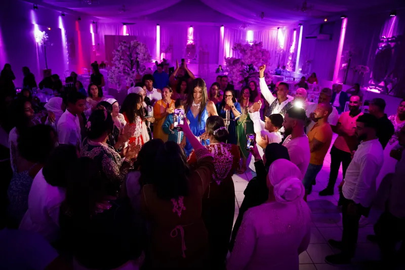 Invités dansant et célébrant lors d'une soirée de mariage sous éclairage violet