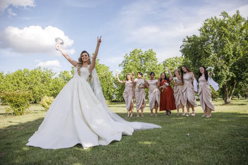 Mariée joyeuse posant avec ses demoiselles d'honneur dans un jardin