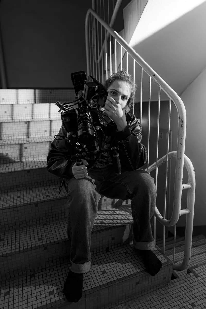 Cadreuse assise dans un escalier avec sa caméra, photo en noir et blanc