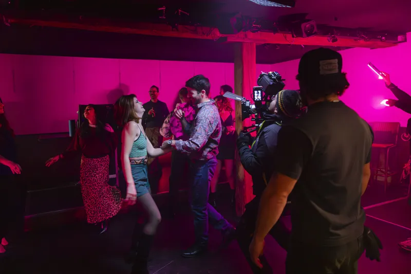 Tournage d'une scène de danse sous un éclairage rose avec caméra
