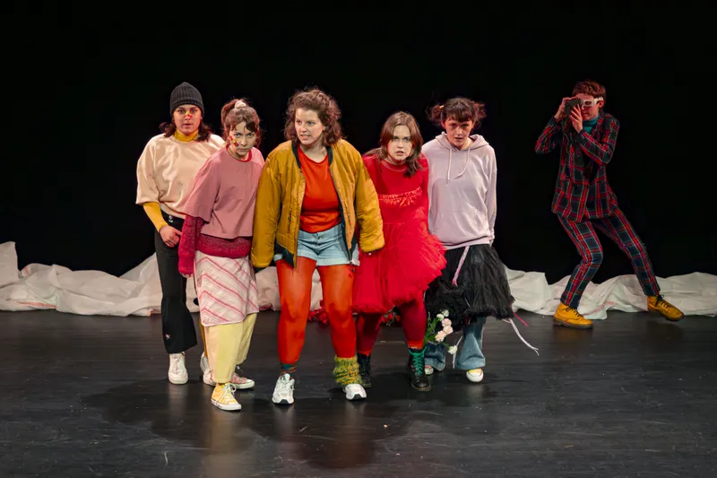 Groupe de jeunes comédiens posant ensemble sur scène en costumes colorés