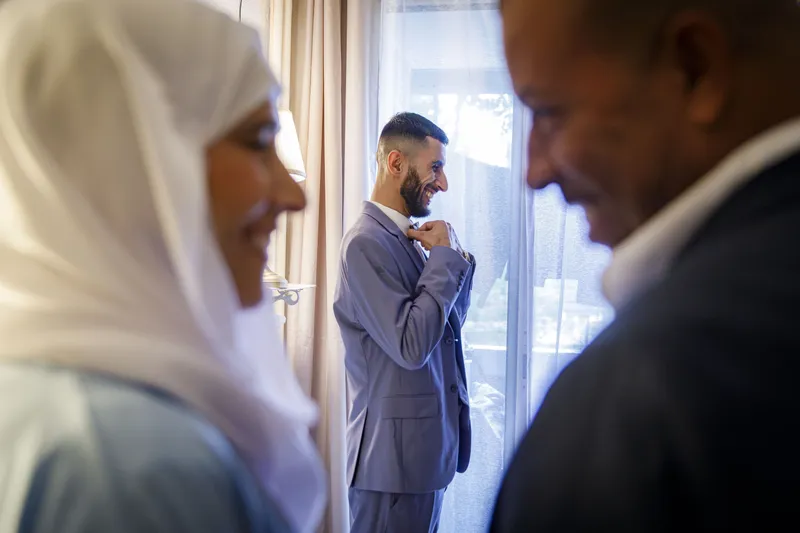 Marié ajustant sa veste devant sa famille lors des préparatifs