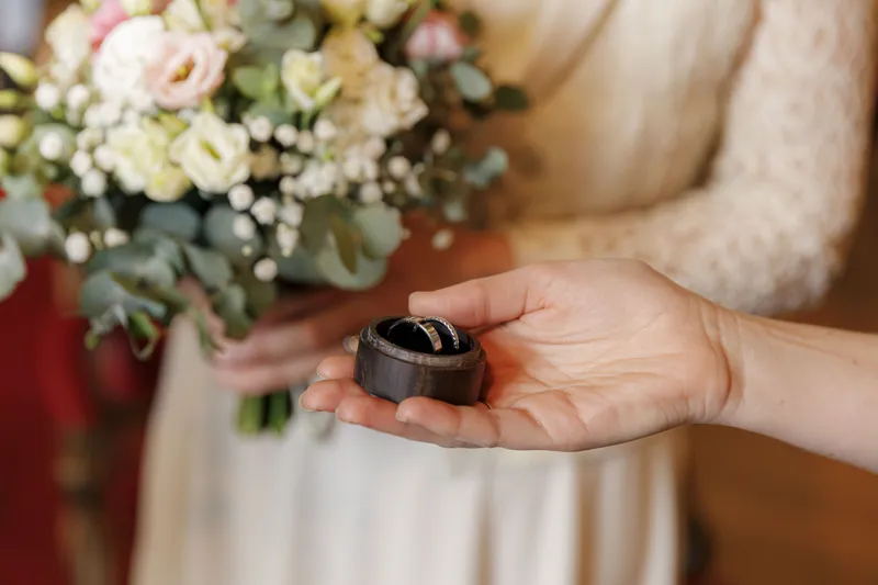 Mariée tenant les alliances dans un écrin avec son bouquet de fleurs