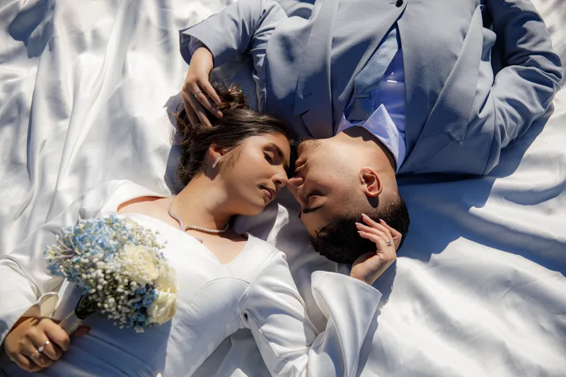 Couple de mariés allongé tête-bêche avec bouquet de fleurs, vue du dessus
