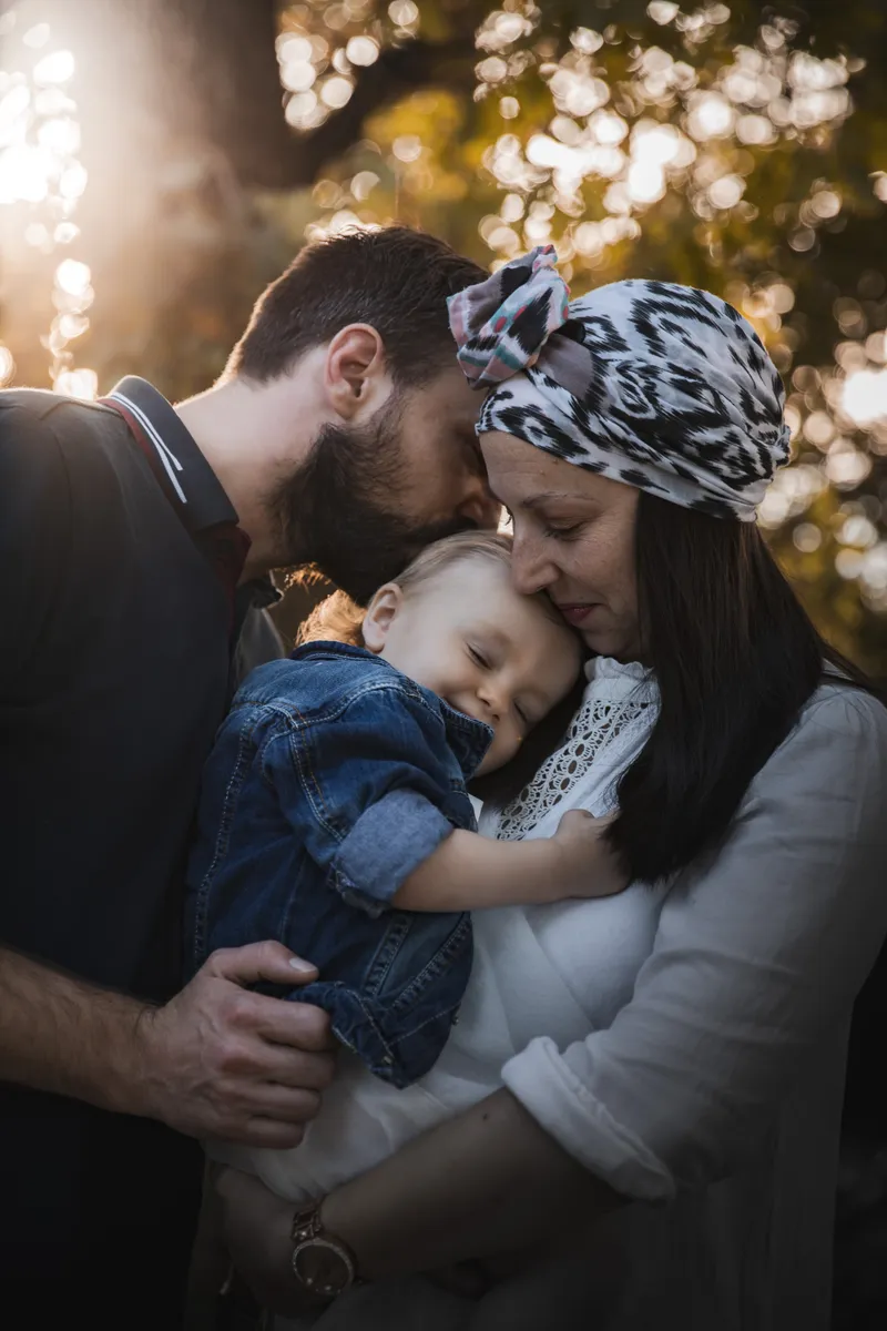 Famille avec un enfant endormi dans les bras des parents en extérieur