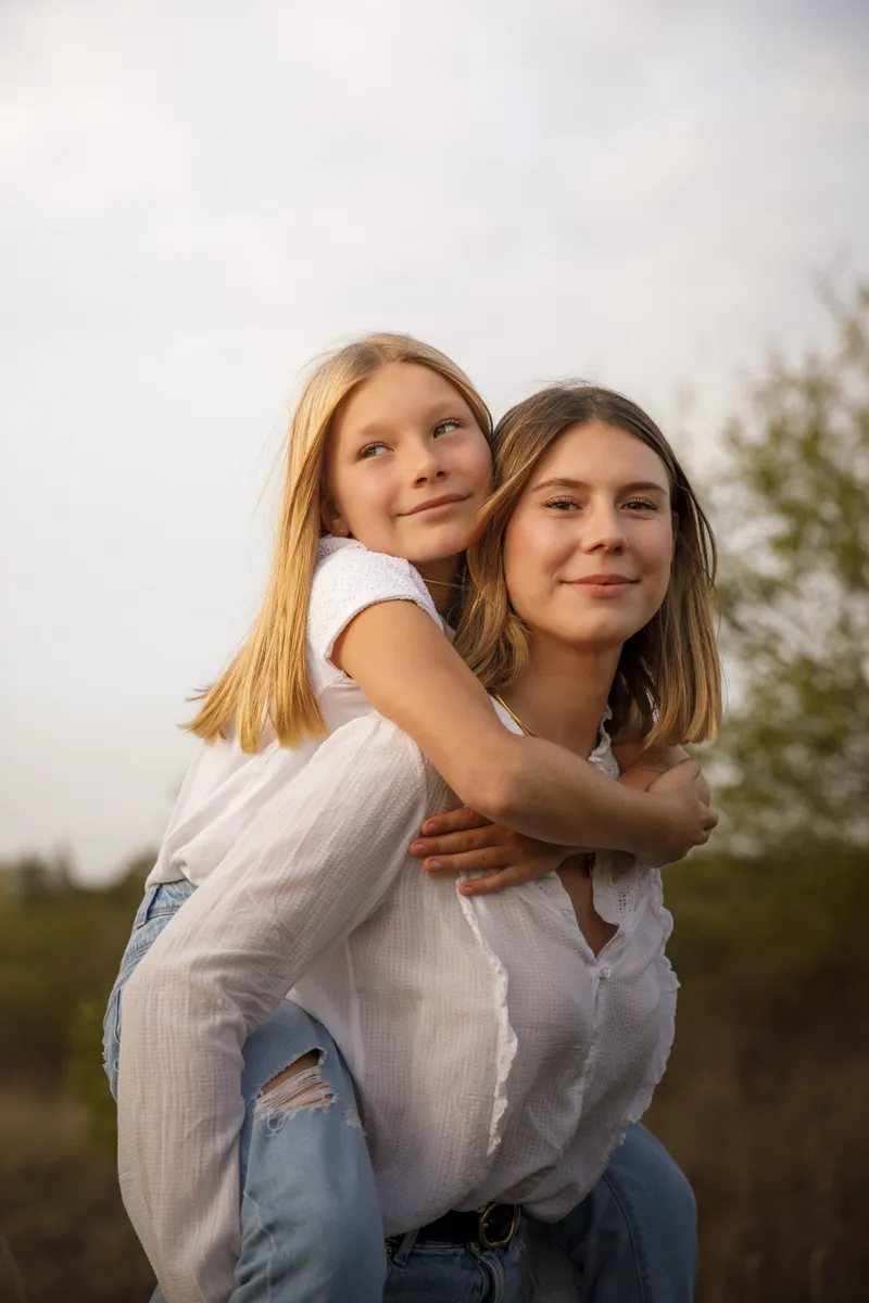 Jeune fille portée sur le dos de sa maman en pleine nature