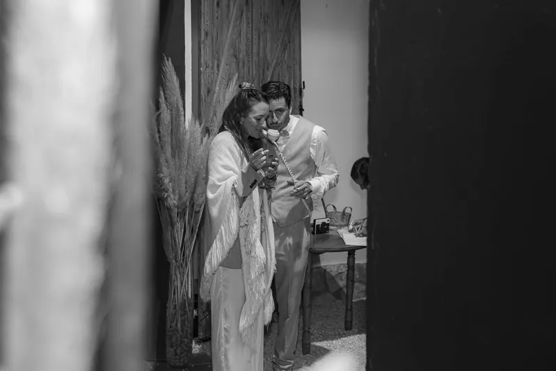 Couple de mariés se regardant en noir et blanc derrière une porte