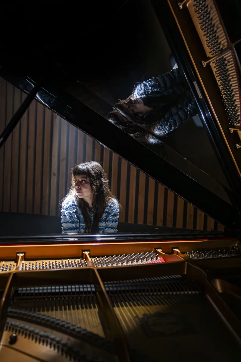 Pianiste jouant dans une salle de concert avec reflet sur le piano
