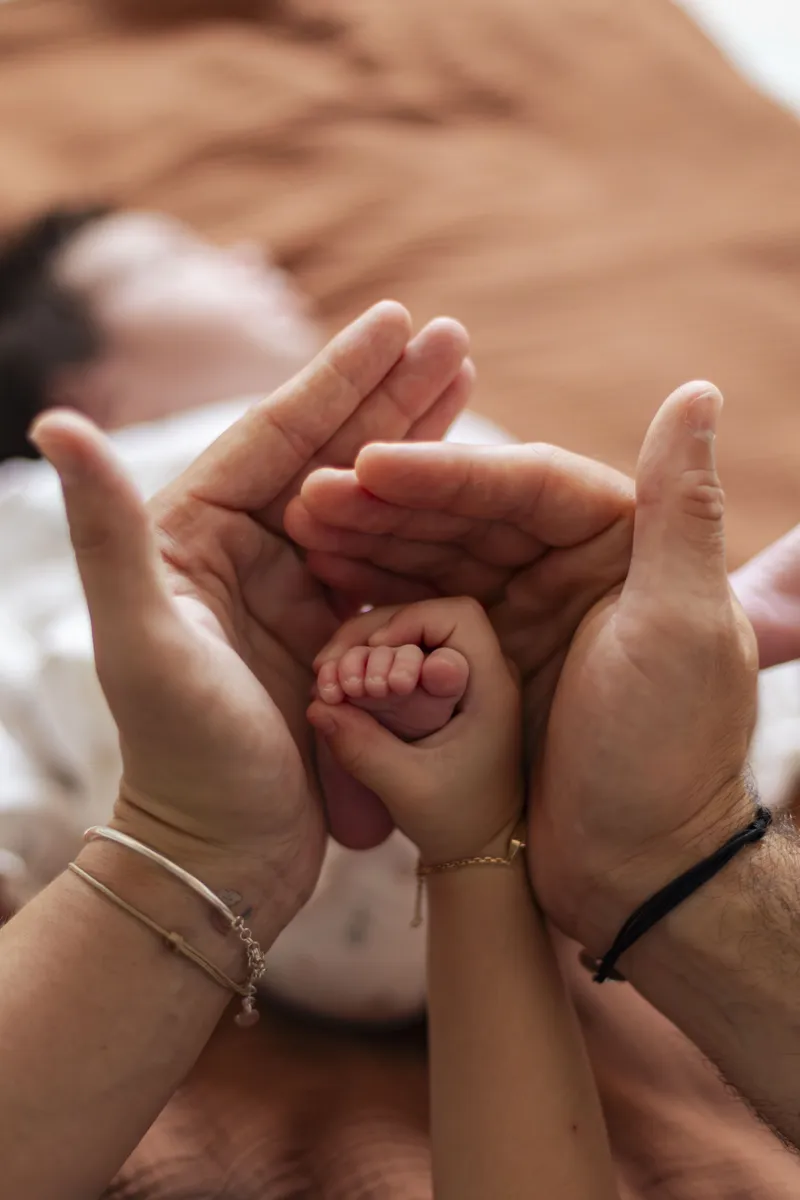 Main du nouveau-né agrippant les doigts de ses parents