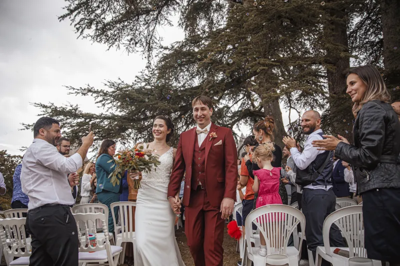 Couple de mariés marchant sous les confettis et les applaudissements des invités
