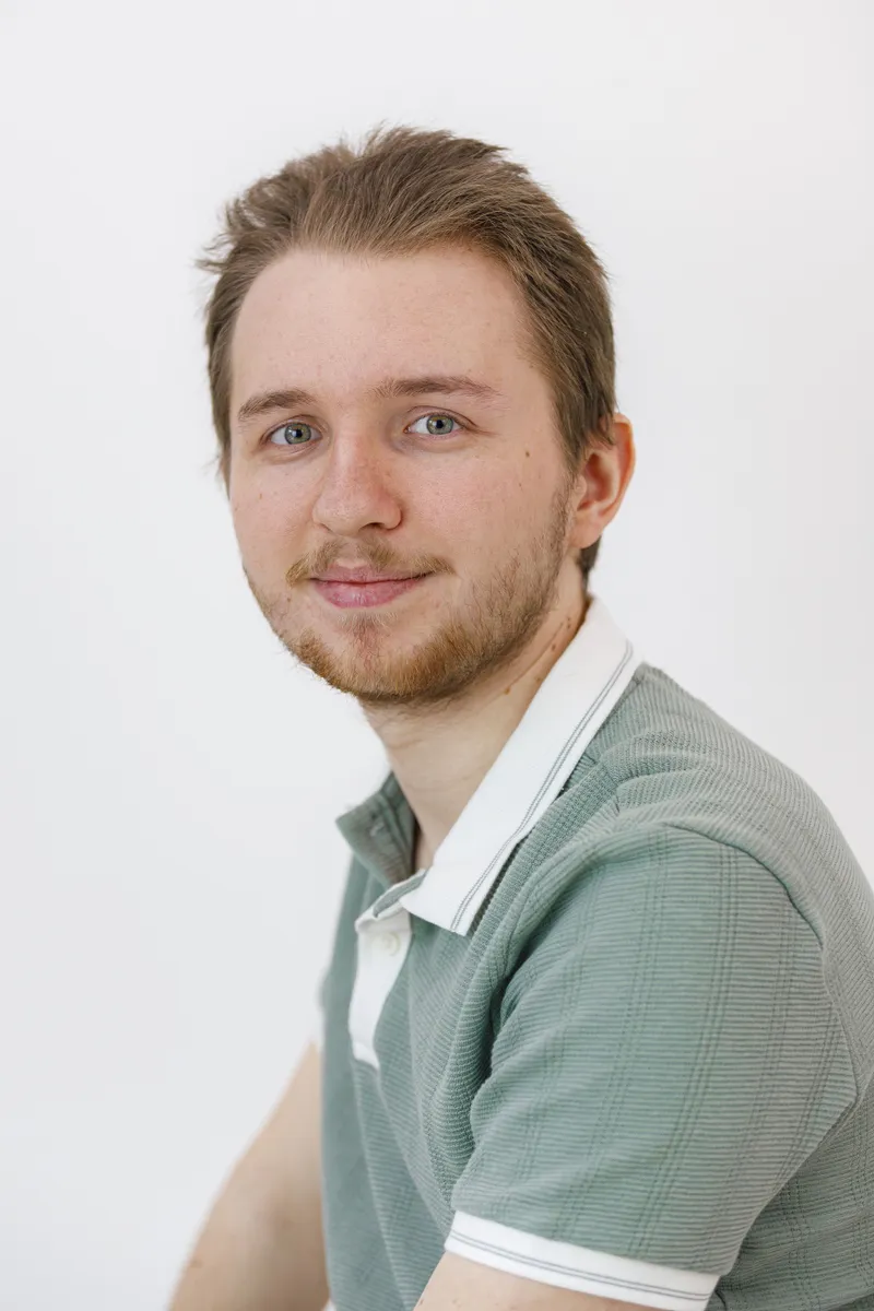 Portrait souriant d'un comédien en polo vert clair sur fond blanc
