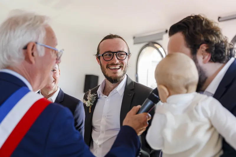 Marié souriant lors de la cérémonie civile avec l'officier d'état civil portant l'écharpe tricolore