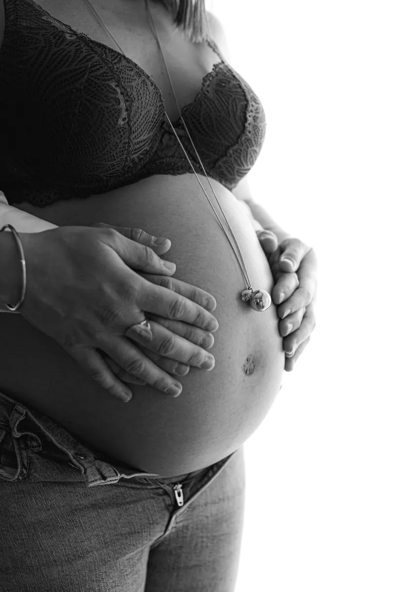 Photo de grossesse en noir et blanc avec les mains sur le ventre arrondi