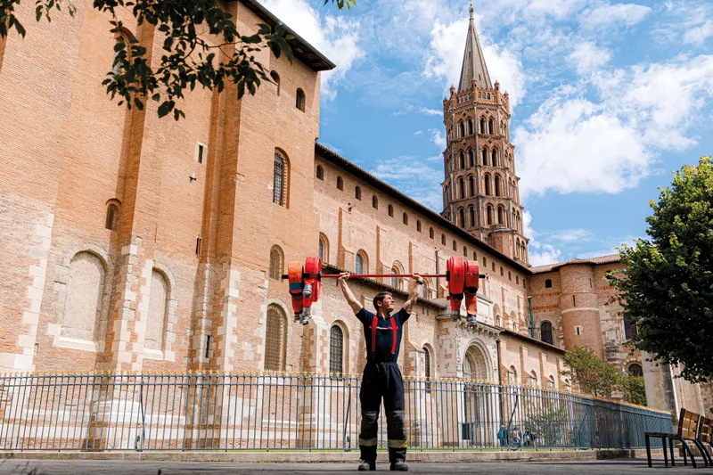 Pompier soulevant des haltères devant la basilique Saint-Sernin à Toulouse