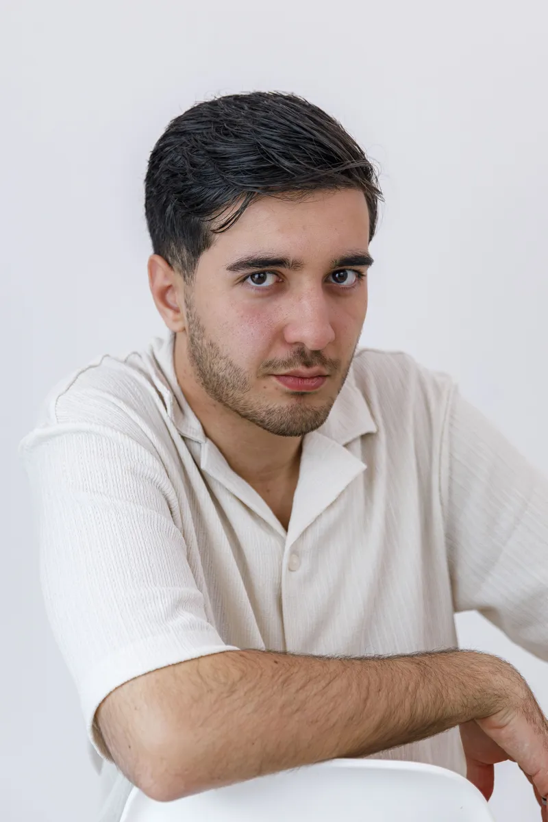 Portrait au regard intense d'un comédien en chemise blanche sur fond clair