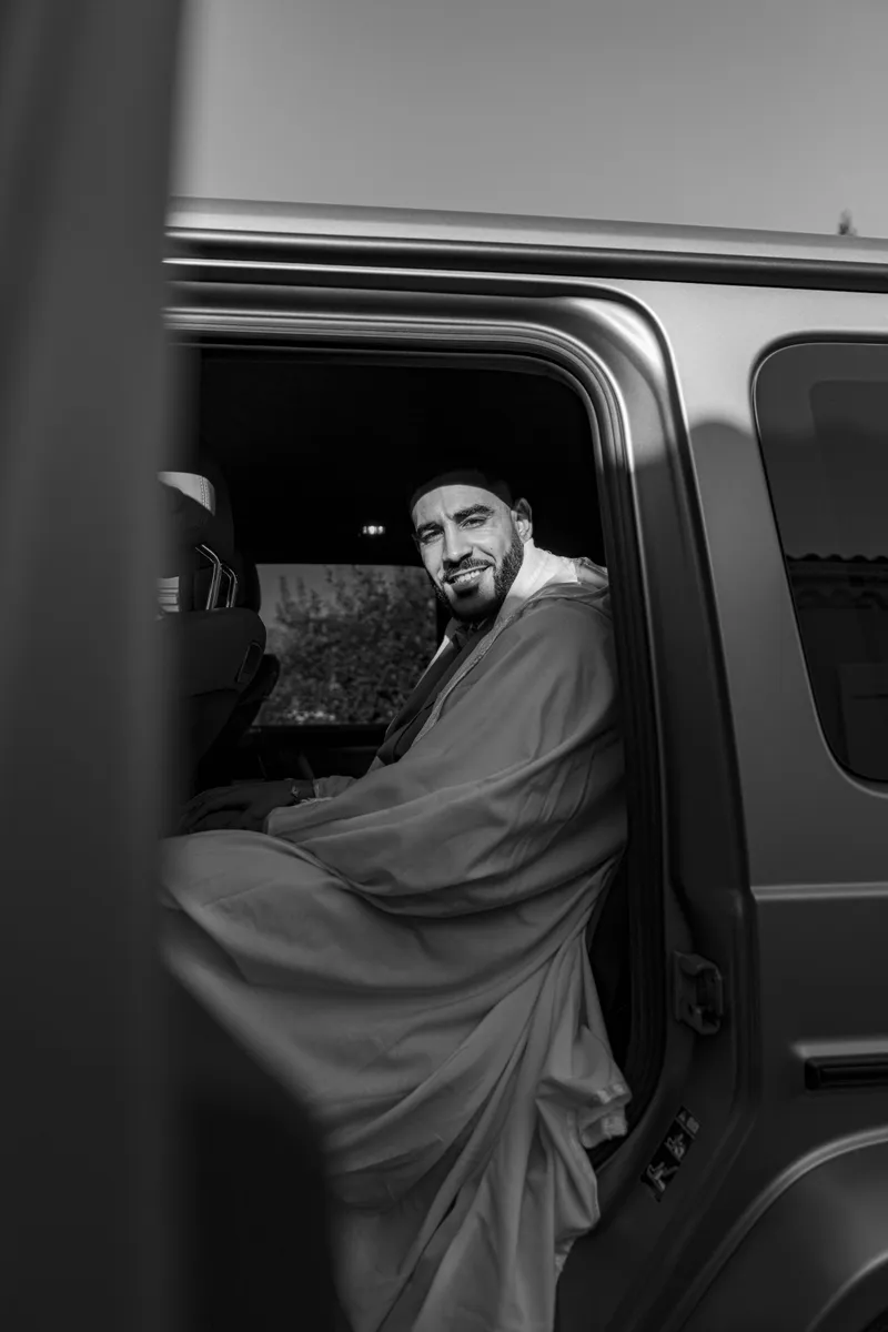 Portrait en noir et blanc d'un marié assis dans une voiture