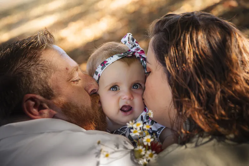 Parents embrassant tendrement leur bébé avec un bandeau fleuri